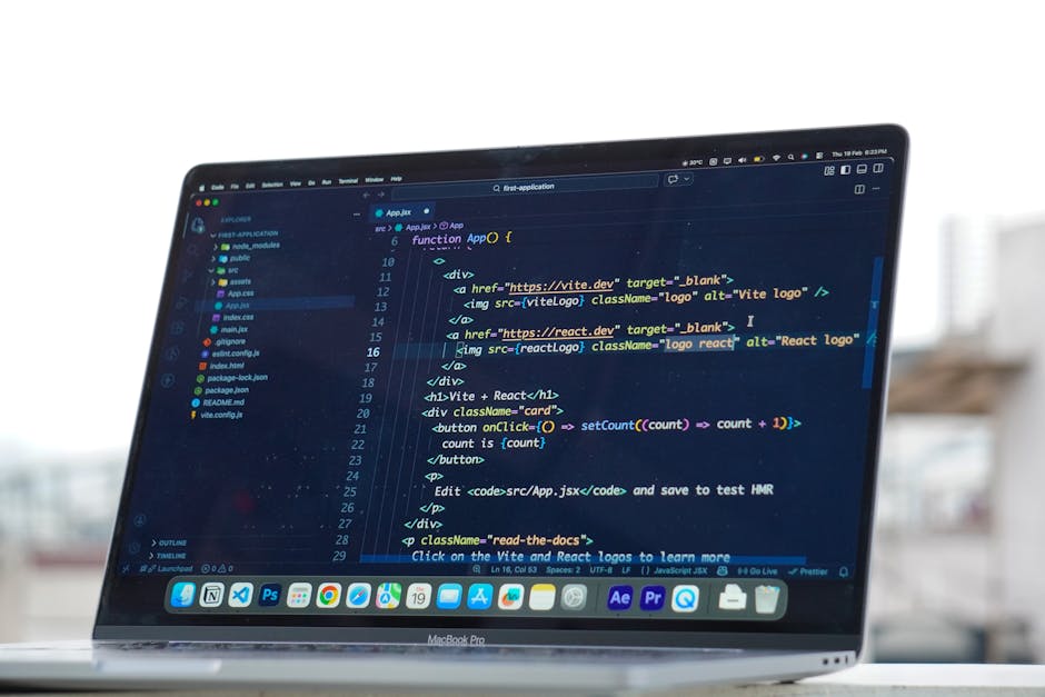 Close-up of a MacBook Pro displaying a dark-themed coding interface with lines of HTML, JavaScript, and CSS code. The screen shows a development environment with a sidebar of files and folders, and a 